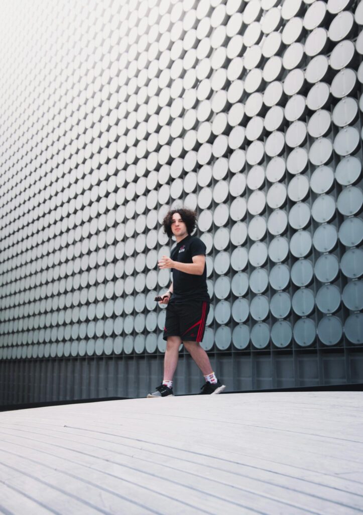 A young person walking past a futuristic architectural facade with geometric patterns in Melbourne.