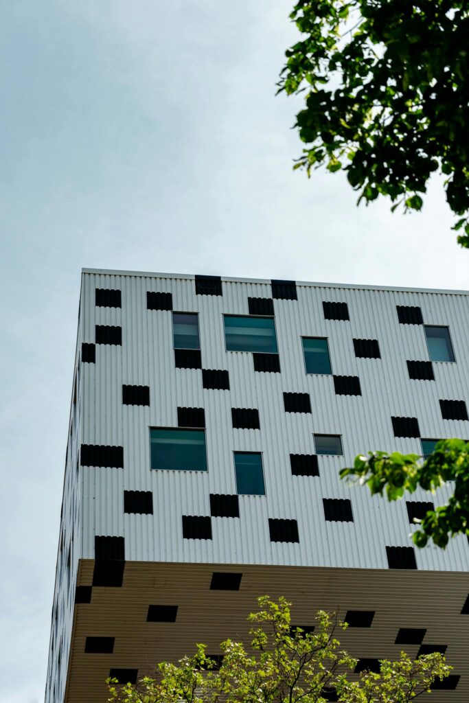 An abstract geometric facade of a modern building with trees in view, emphasizing contemporary design.