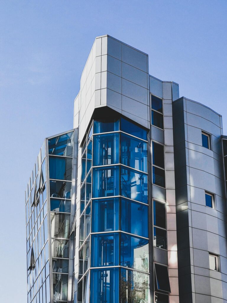 Contemporary glass skyscraper reflecting the Bucharest skyline under a clear blue sky.