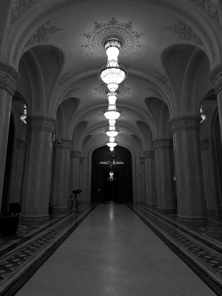 Elegant black-and-white view of an Art Deco hallway illuminated by ornate chandeliers.